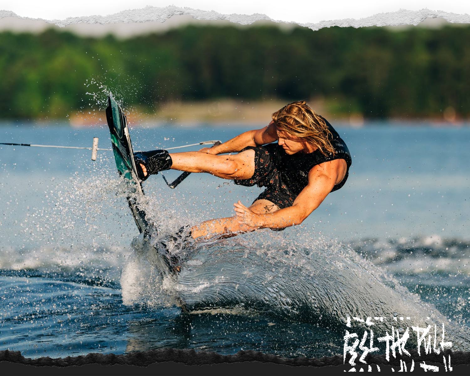 Man wakeboarding in black vest mid-turn with water spraying.
