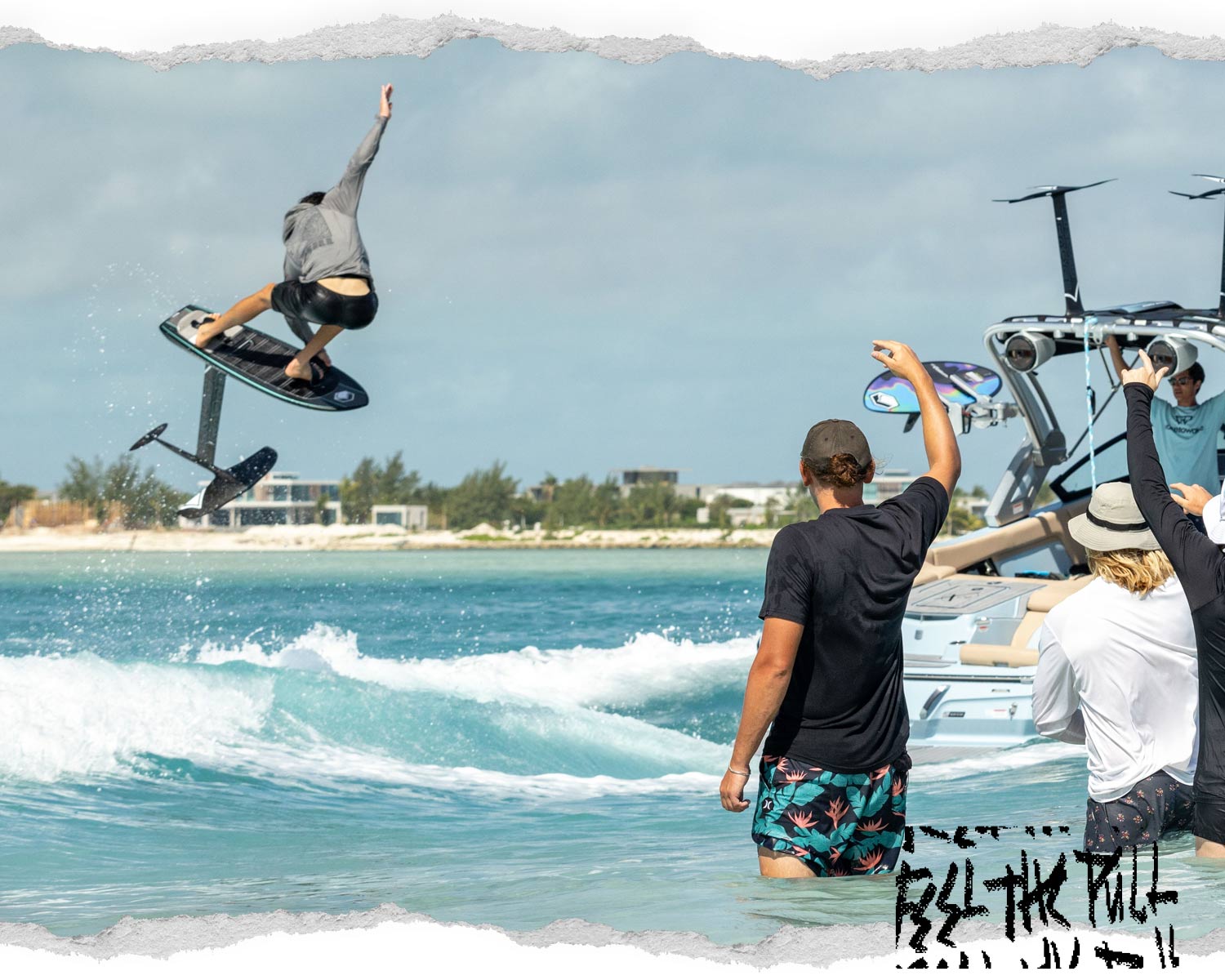 Rider launches on foil board as friends cheer from boat in turquoise water.