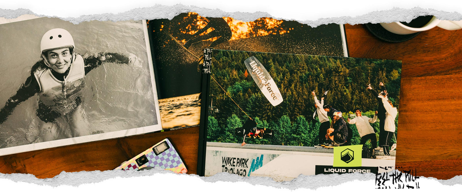 Overhead view of a wooden table featuring wakeboarding books, one opened and one closed.