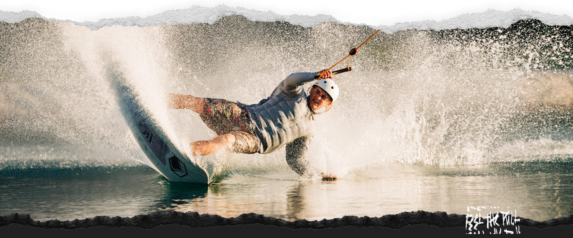 Rider doing aggressive carve on white Noodle wakeboard at golden hour.