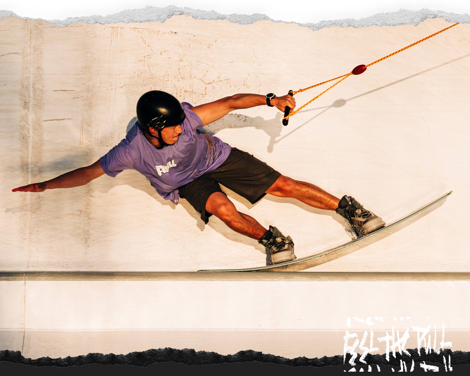Rider carves on a wall ride wearing a helmet and purple tee with a Peak wakeboard and boots.