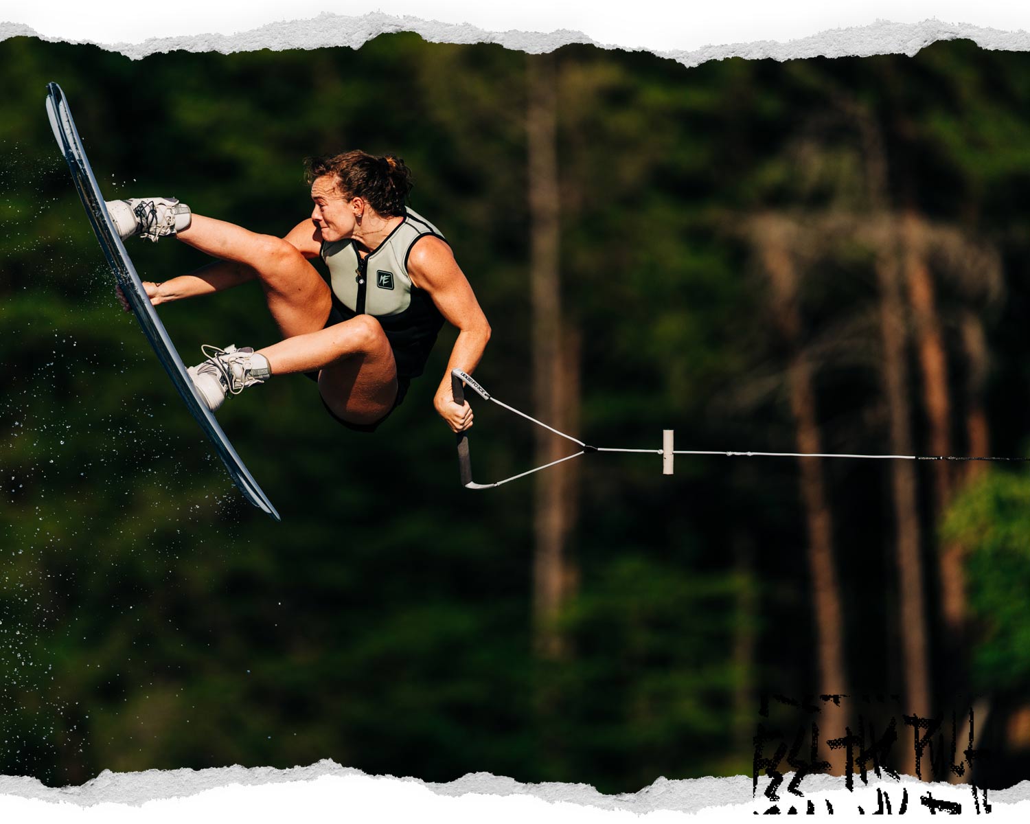 Wakeboarder in midair grab trick wearing white bindings and life vest.