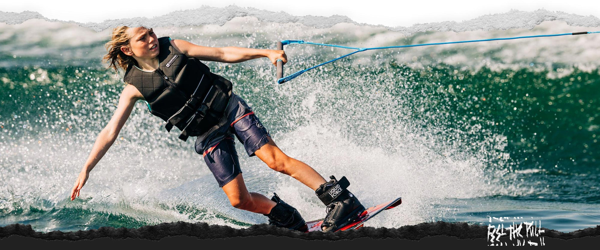 Youth wakeboarder in black vest riding with spray and wearing black Liquid Force boots.
