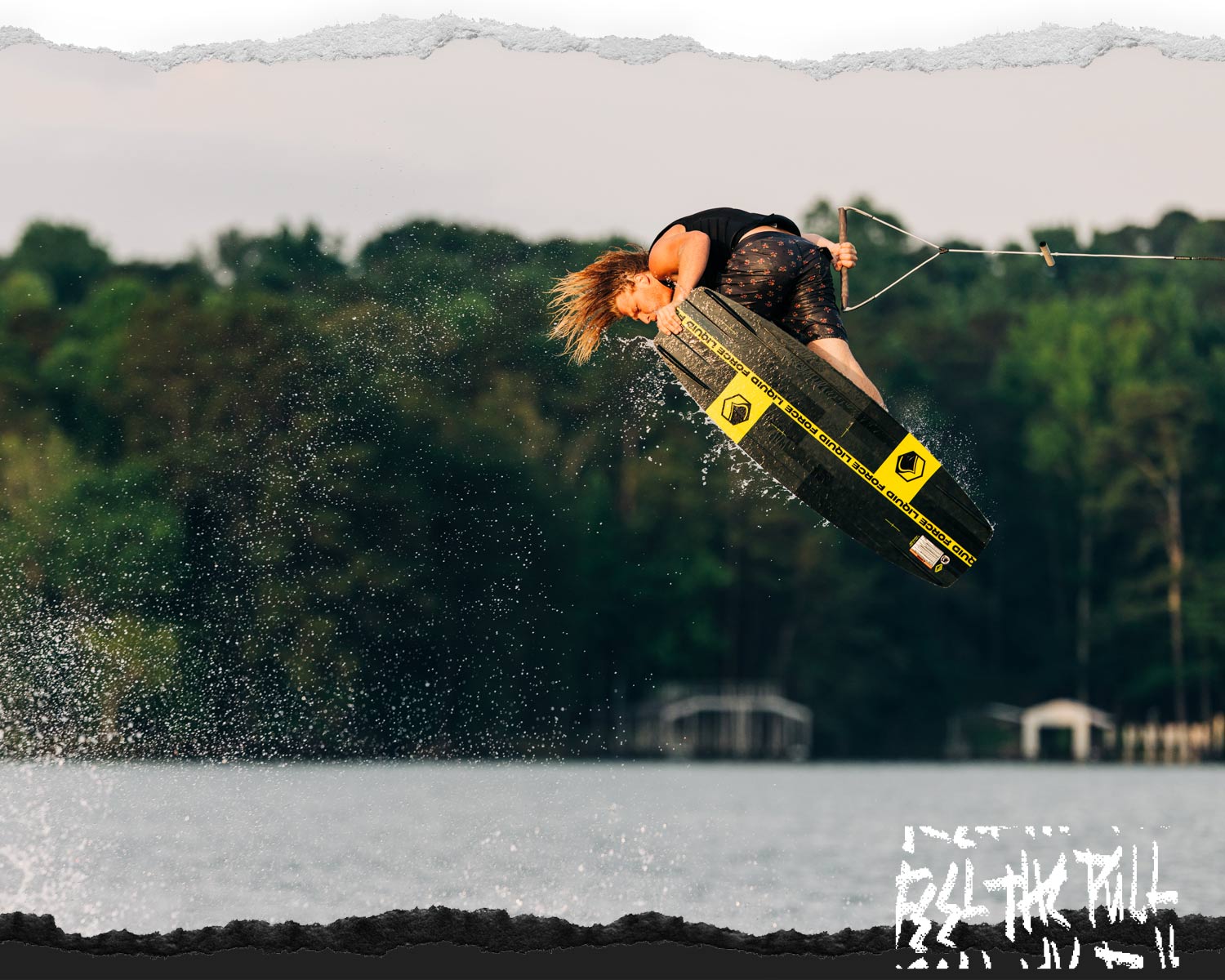 Rider launches over water on black and yellow Liquid Force wakeboard.
