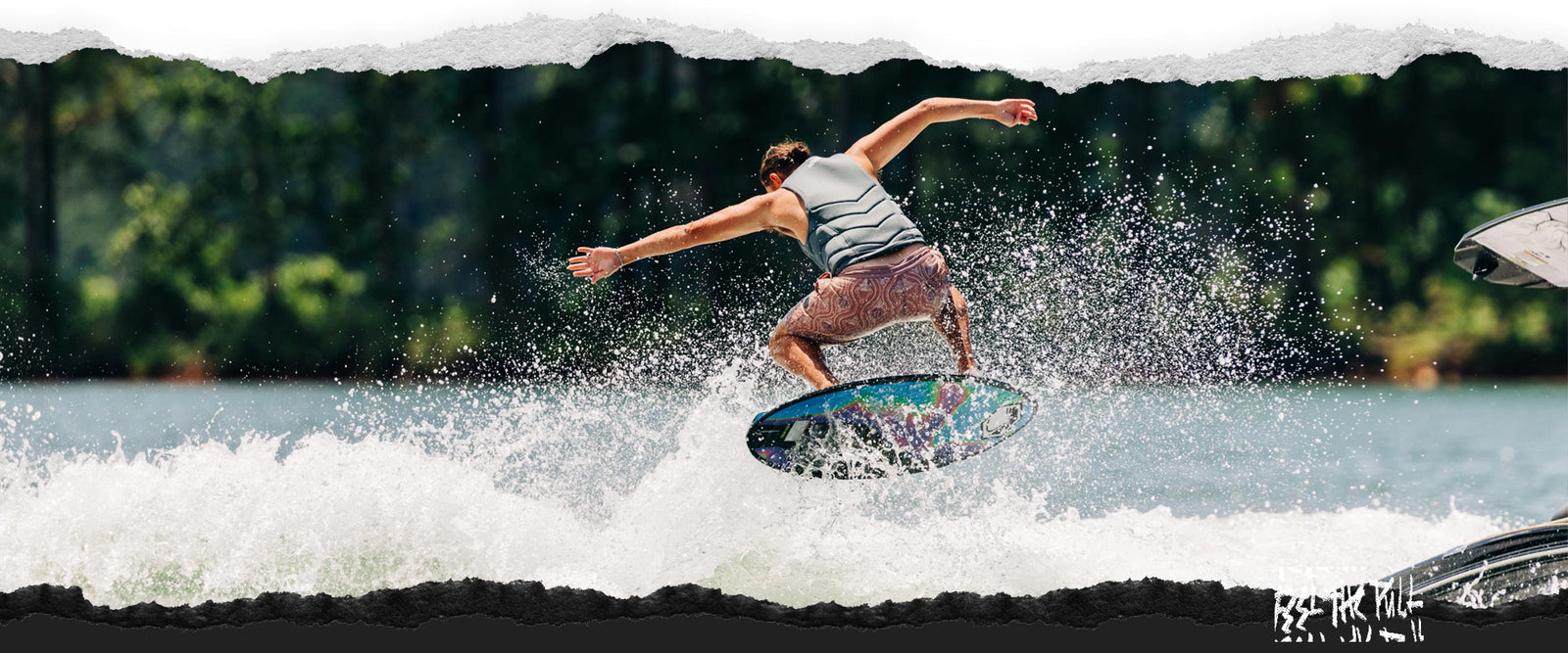 Rider landing a trick on the Liquid Force Reign Wakesurfer in a gray vest.