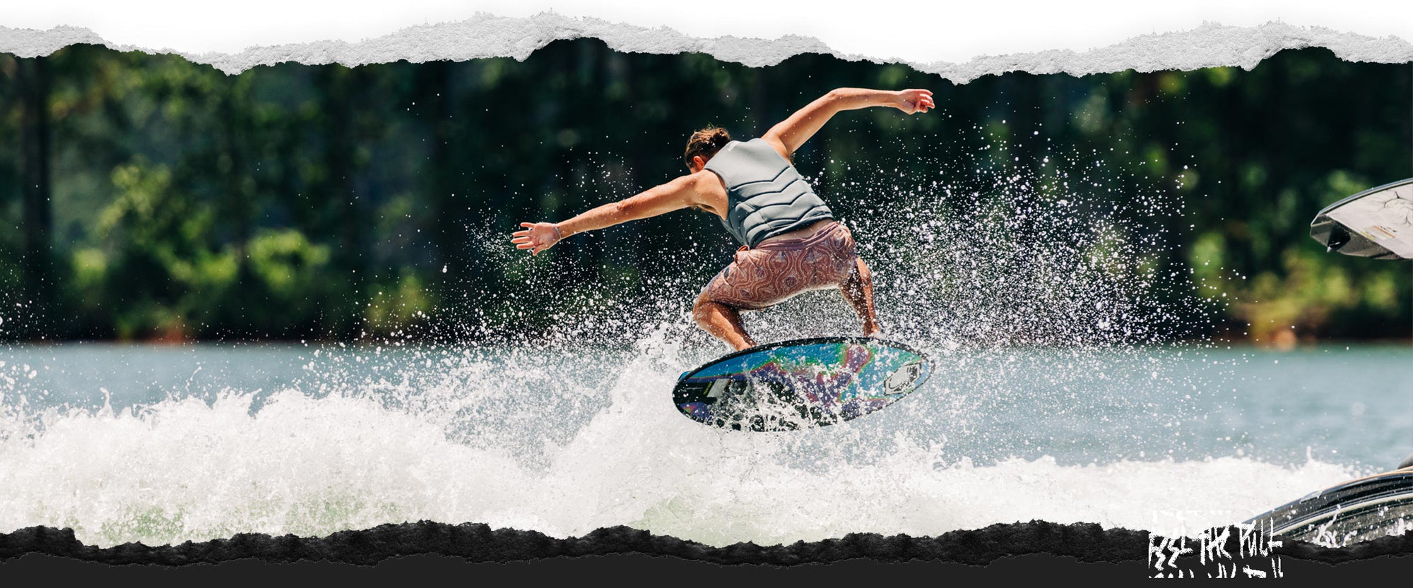 Rider landing a trick on the Liquid Force Reign Wakesurfer in a gray vest.