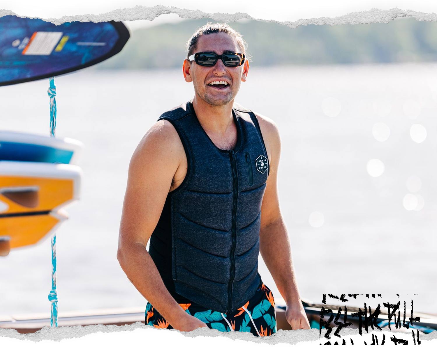 Smiling man wearing the Liquid Force Squad Comp Denim Vest on a dock.