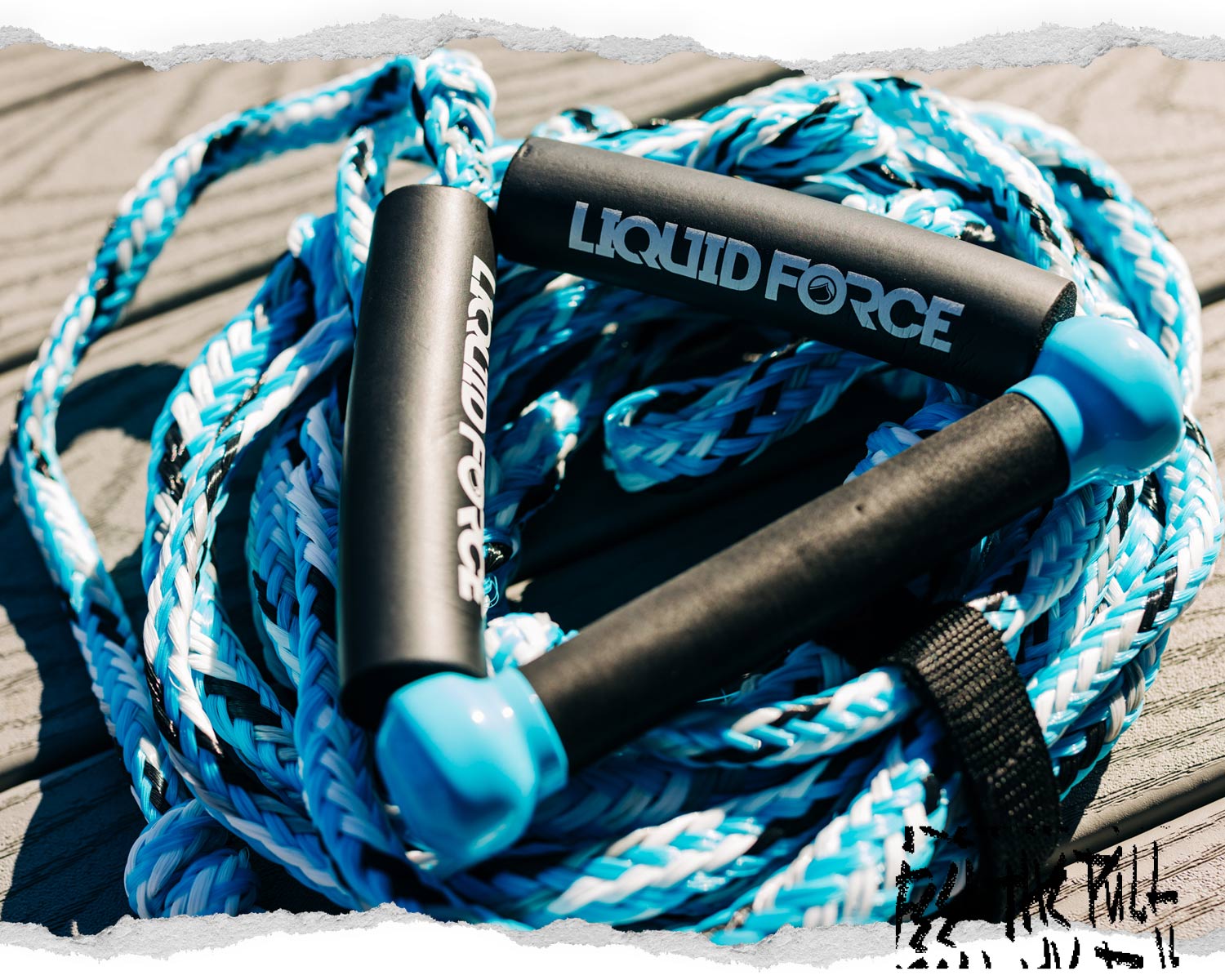 Blue and white Liquid Force handle and rope resting on wood planks.