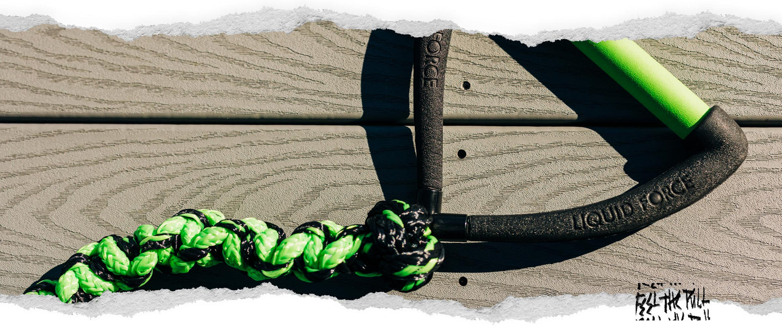 Close-up of black and green Liquid Force handle with coiled rope.