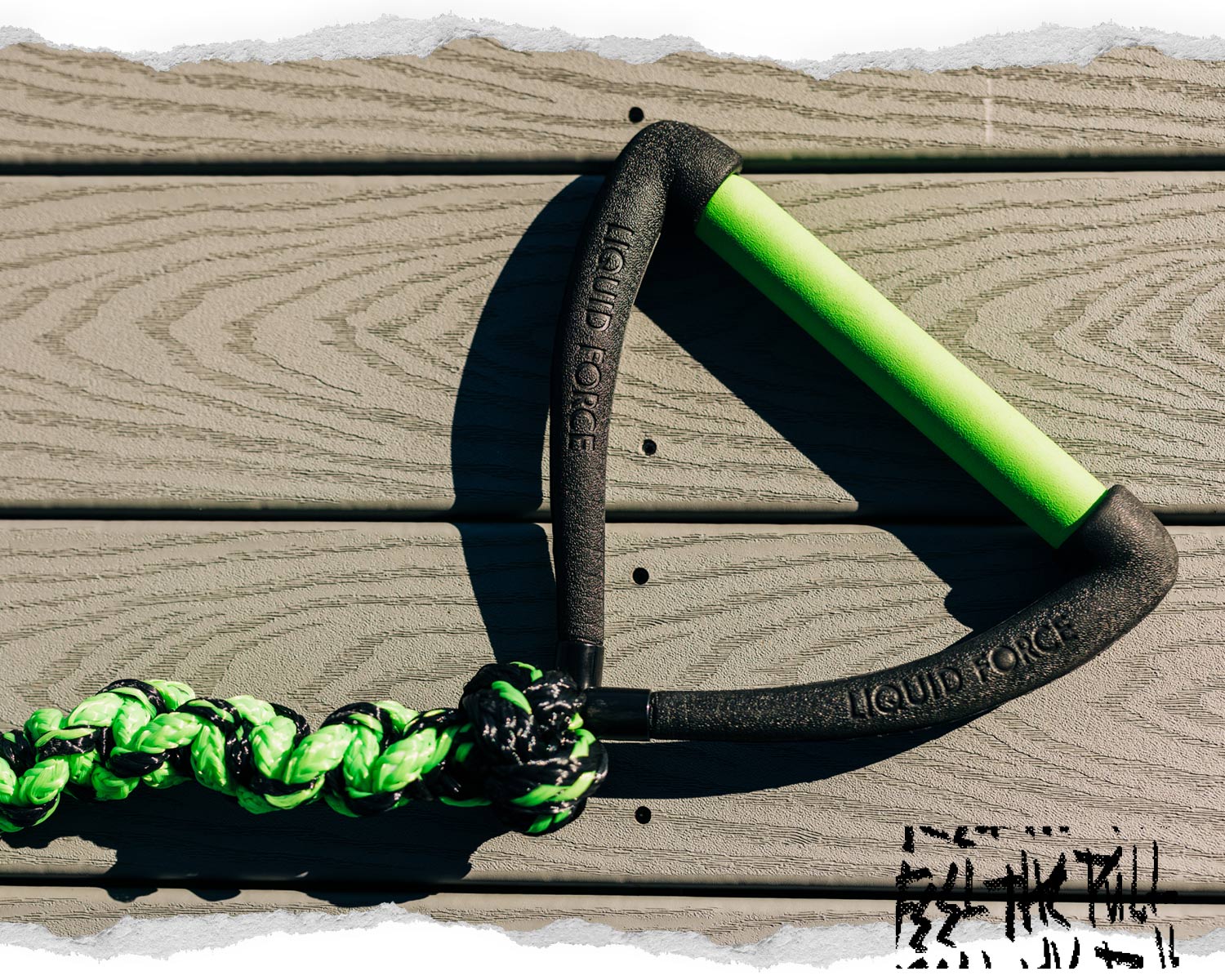 Close-up of black and green Liquid Force handle with coiled rope.