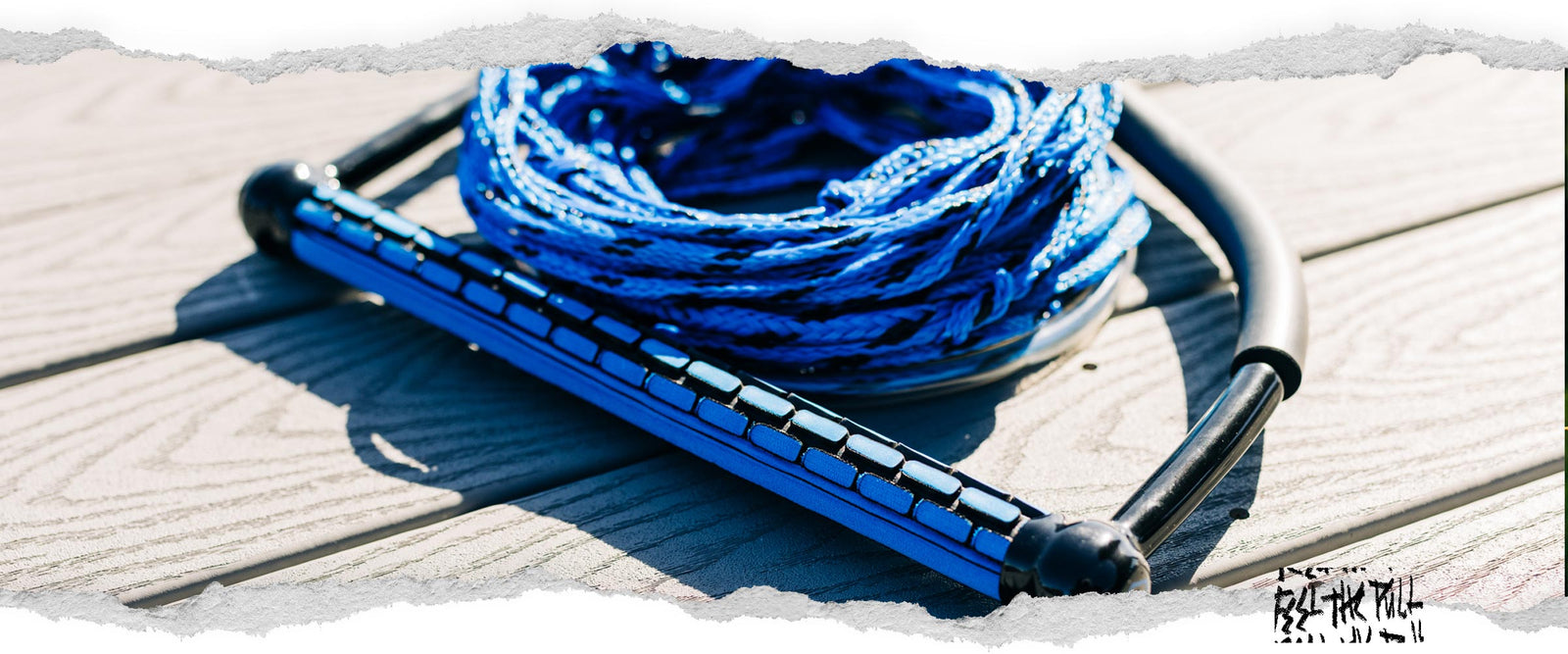 Mango TR9 de Liquid Force azul con cuerda a juego enrollada a su lado en el muelle.