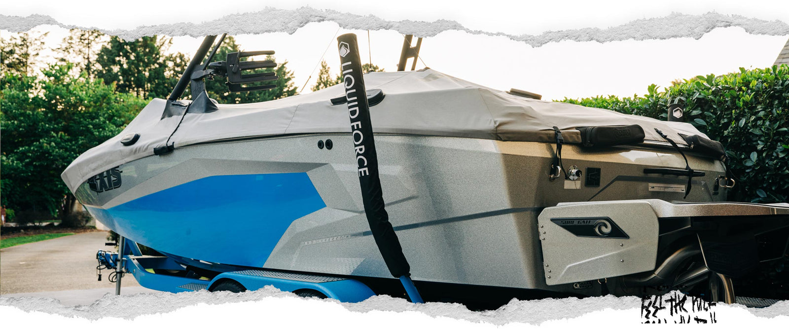 Side view of covered wake boat on trailer with Liquid Force trailer guides.