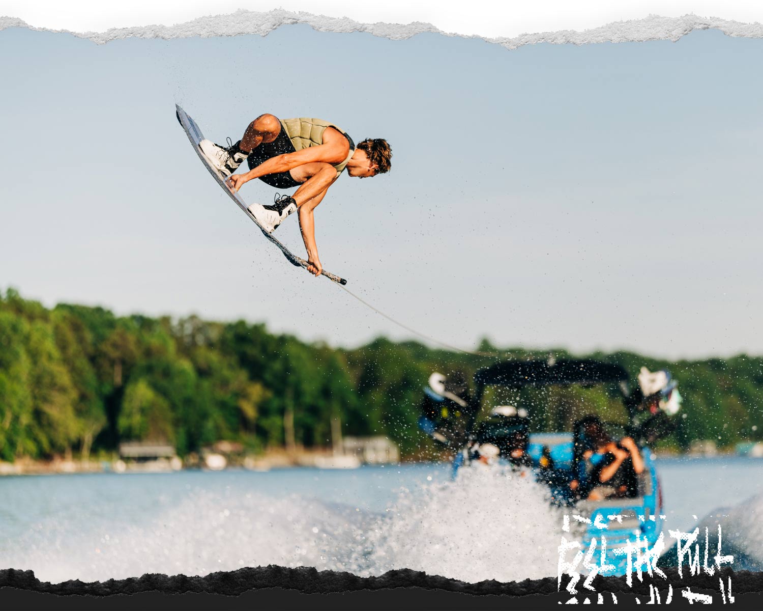 Rider airborne above boat wake on gray Unity Aero wakeboard.