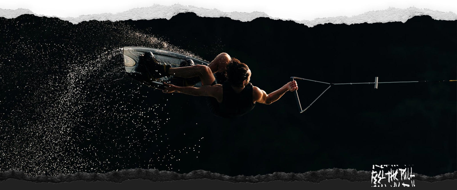 Rider airborne with bent knees and handle in hand against dark backdrop.