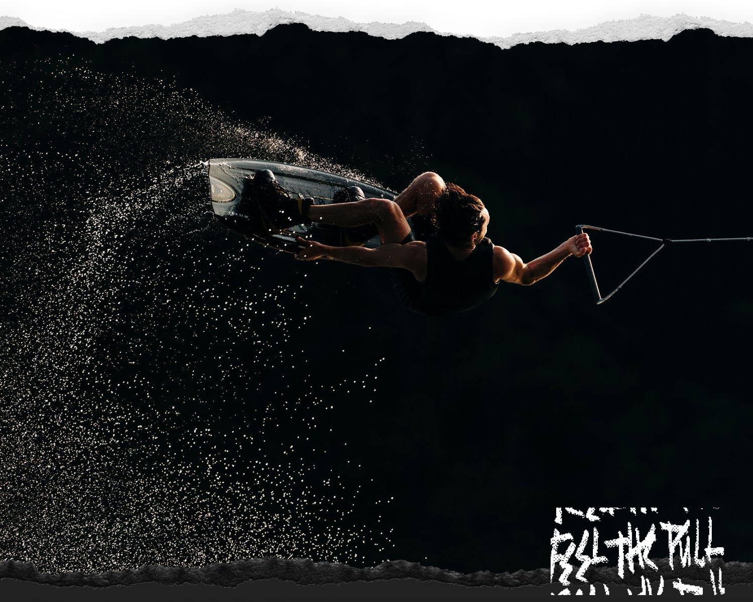 Rider airborne with bent knees and handle in hand against dark backdrop.