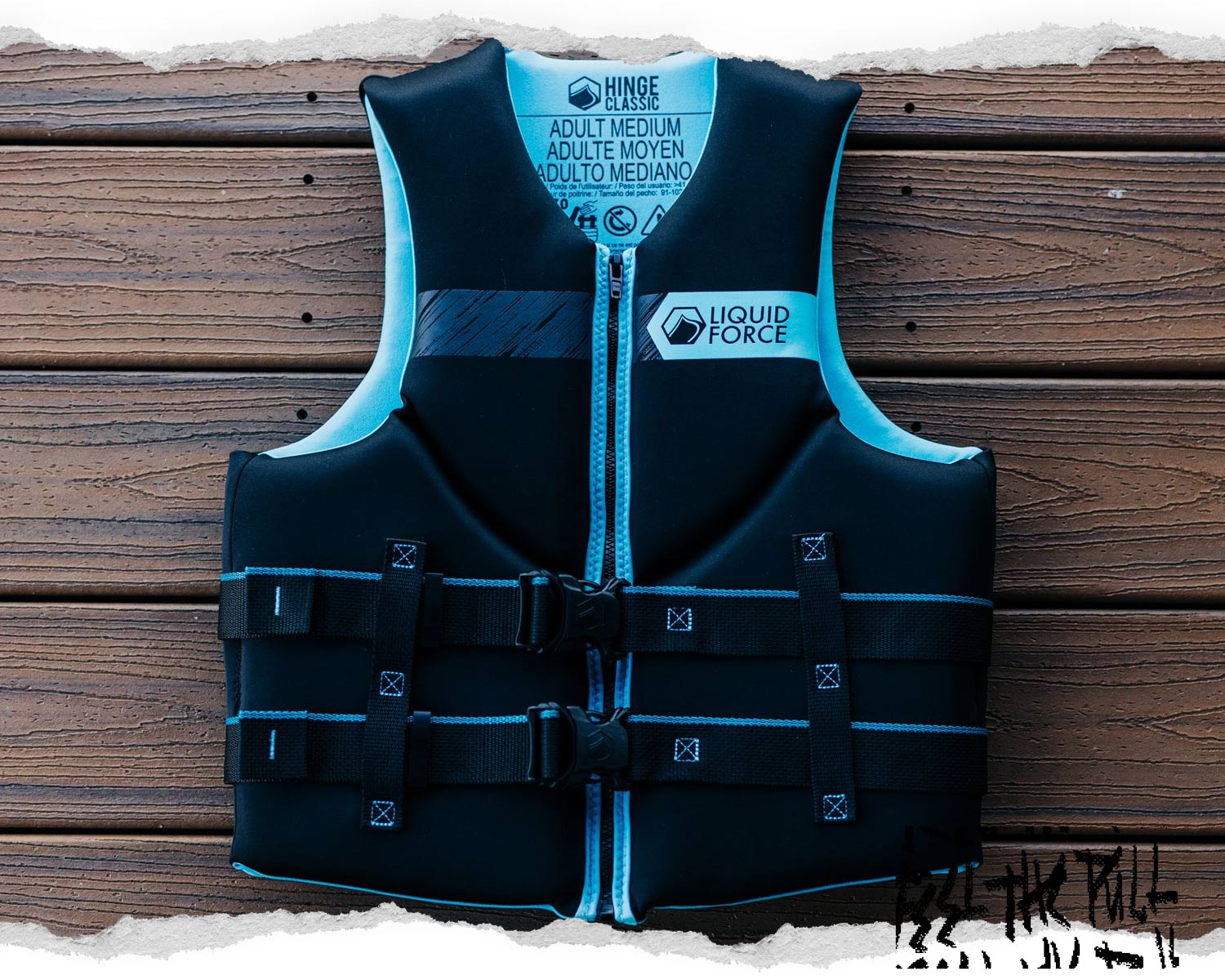 Black and aqua Classic Hinge CGA vest with Liquid Force logo laid flat on wood planks.