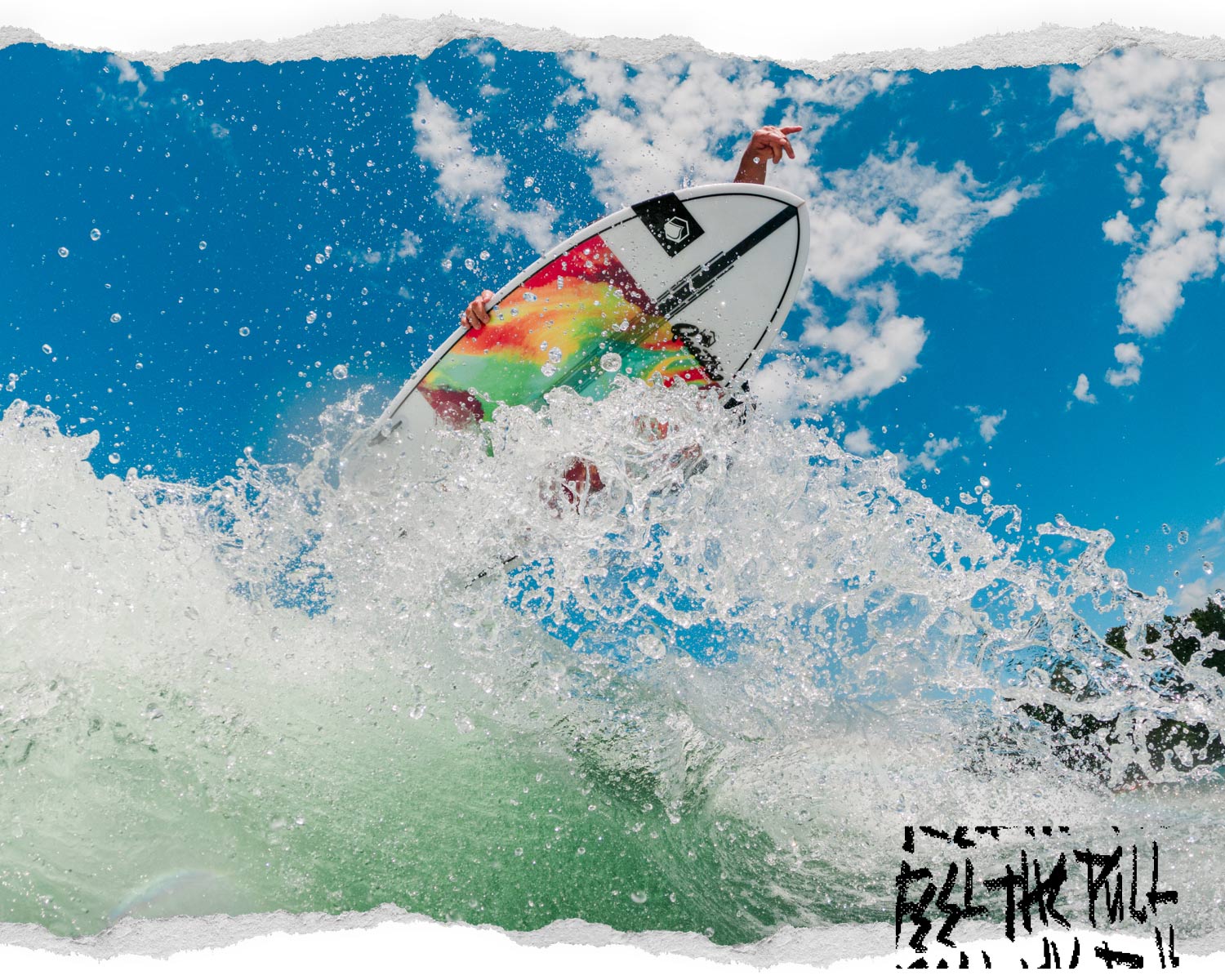 Bright surfboard with tie-dye colors carving through water against blue sky.