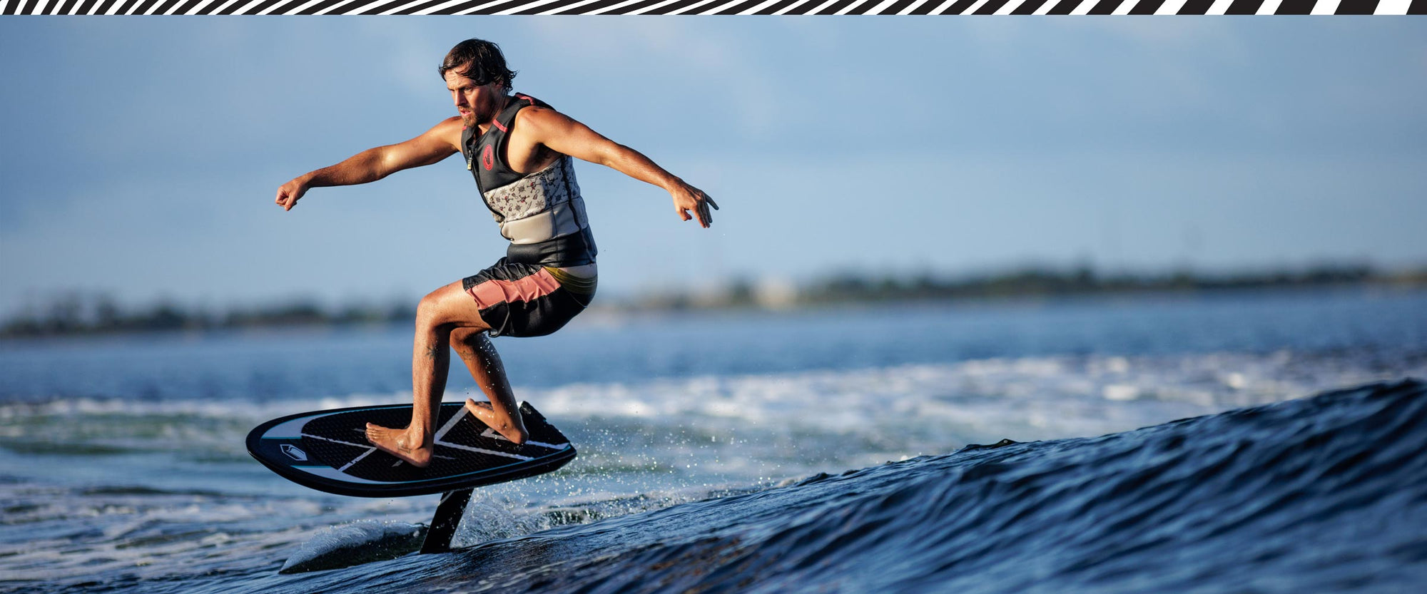 Rider foiling smoothly on Carbon Horizon 1200 FuseLock front wing across gentle blue water.