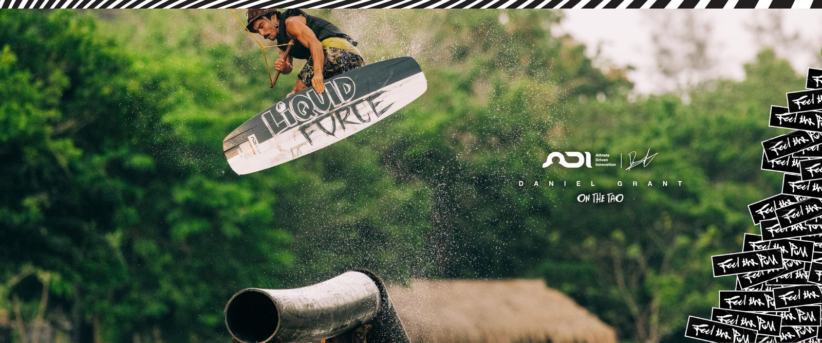 Wakeboarder launching off a rail, grabbing the TAO board mid-air with water spraying.