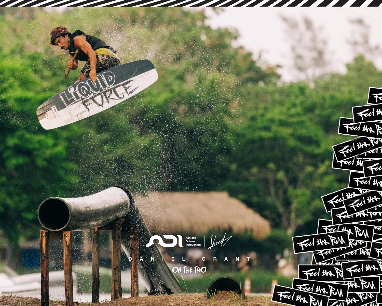 Wakeboarder launching off a rail, grabbing the TAO board mid-air with water spraying.