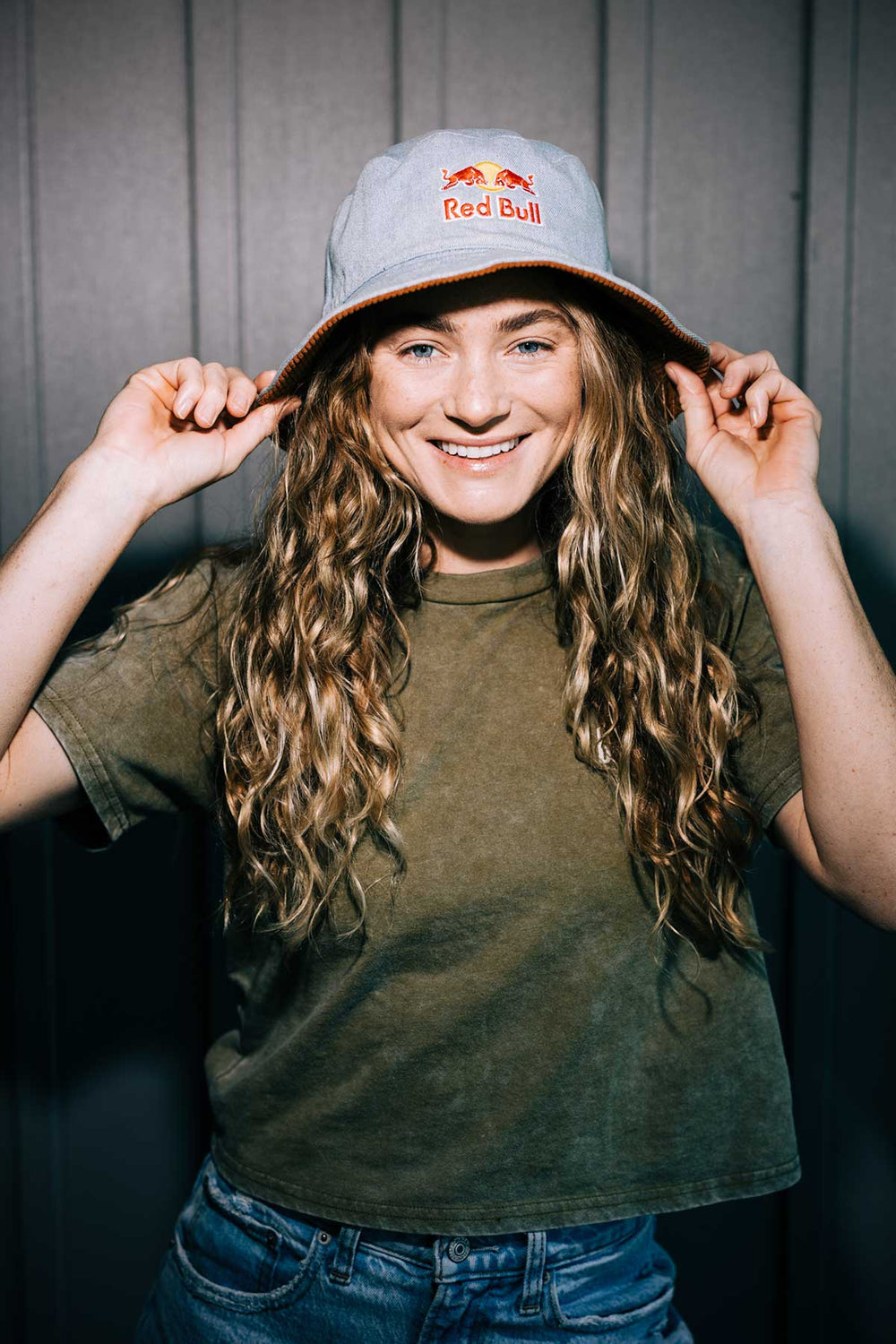 A smiling person in a Red Bull hat and green shirt stands out in the dark.