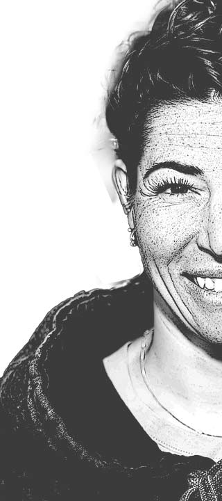 Freckled, smiling person with short hair in a monochrome portrait.